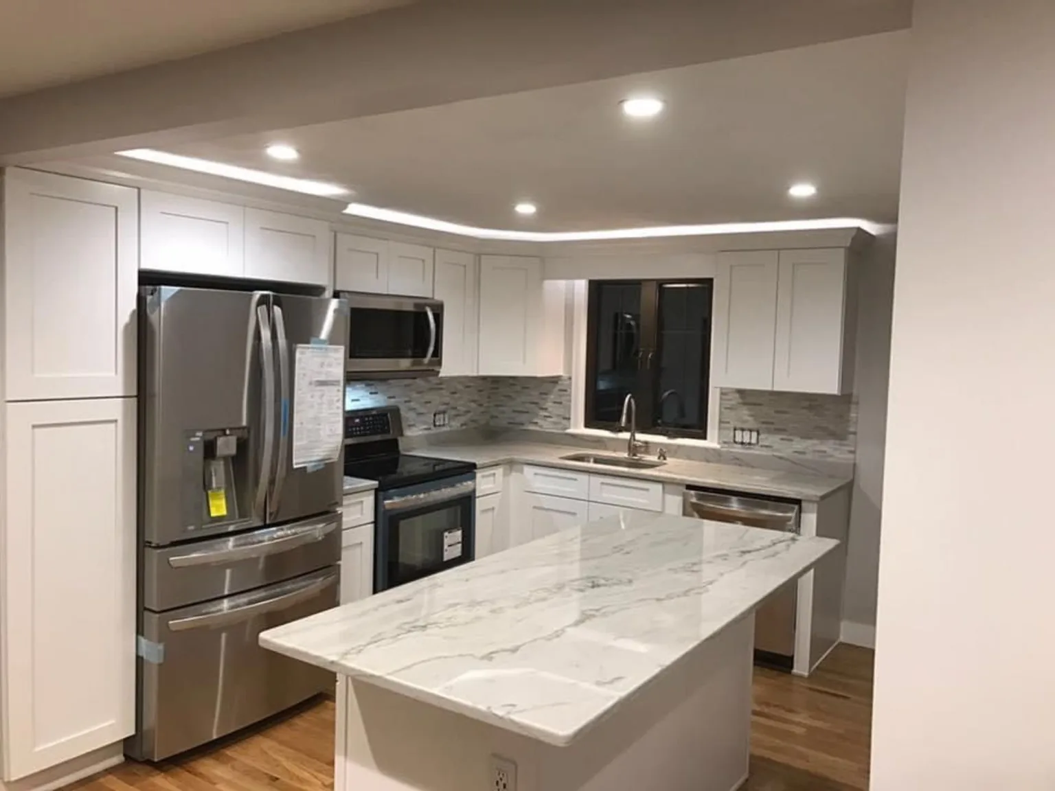 White kitchen remodel with island and stainless appliances